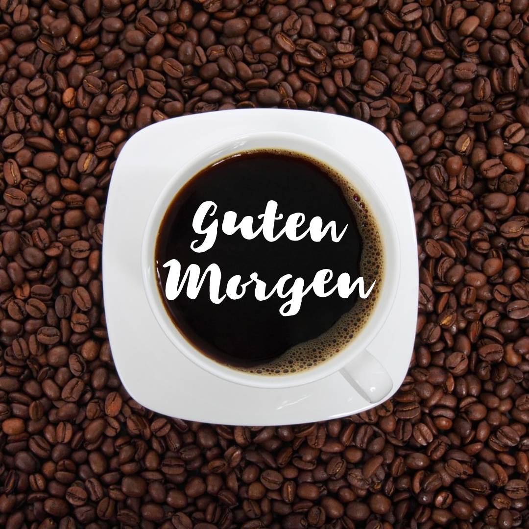 Eine Tasse Kaffee auf Kaffeebohnen mit Guten Morgen Text